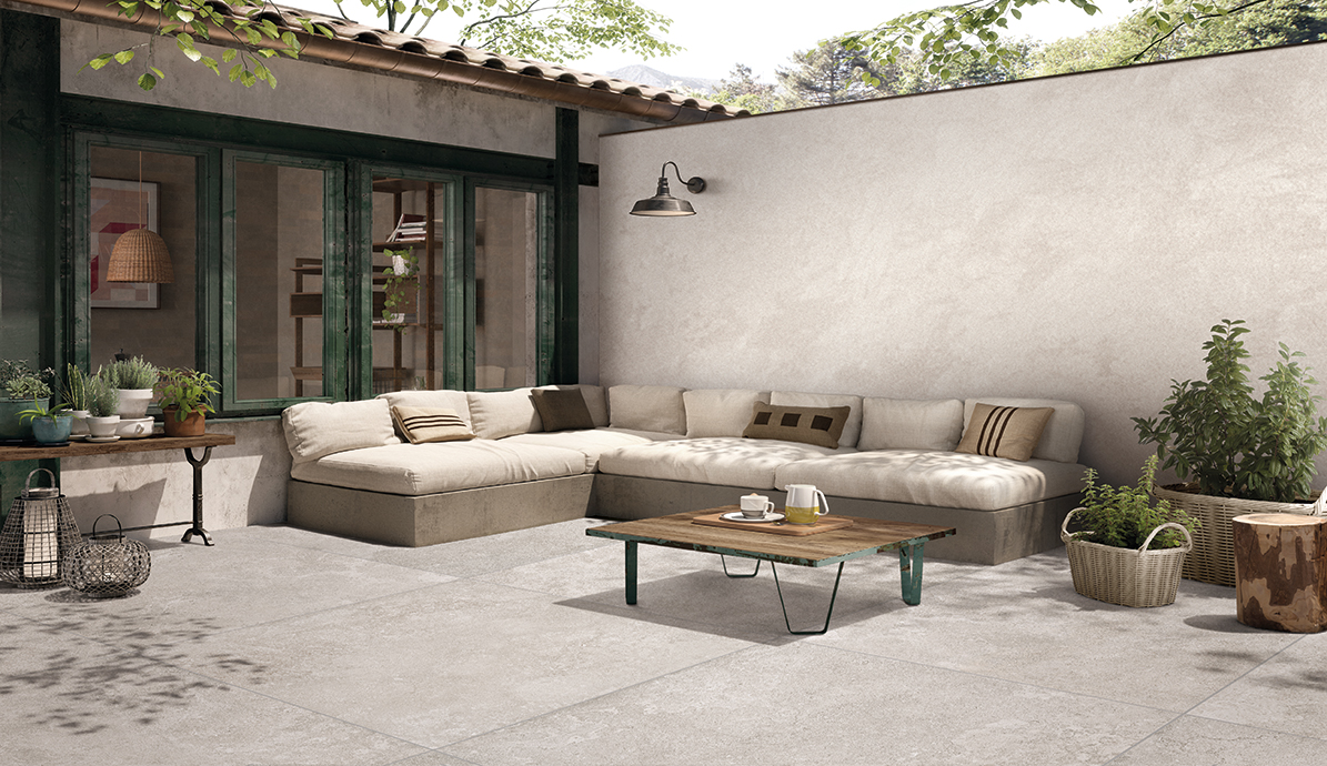 Gartenset mit beiger Eckcouch und Holztisch auf Terrasse Bequeme beige Eckcouch und Holztisch auf einer sonnigen Terrasse umgeben von Pflanzen