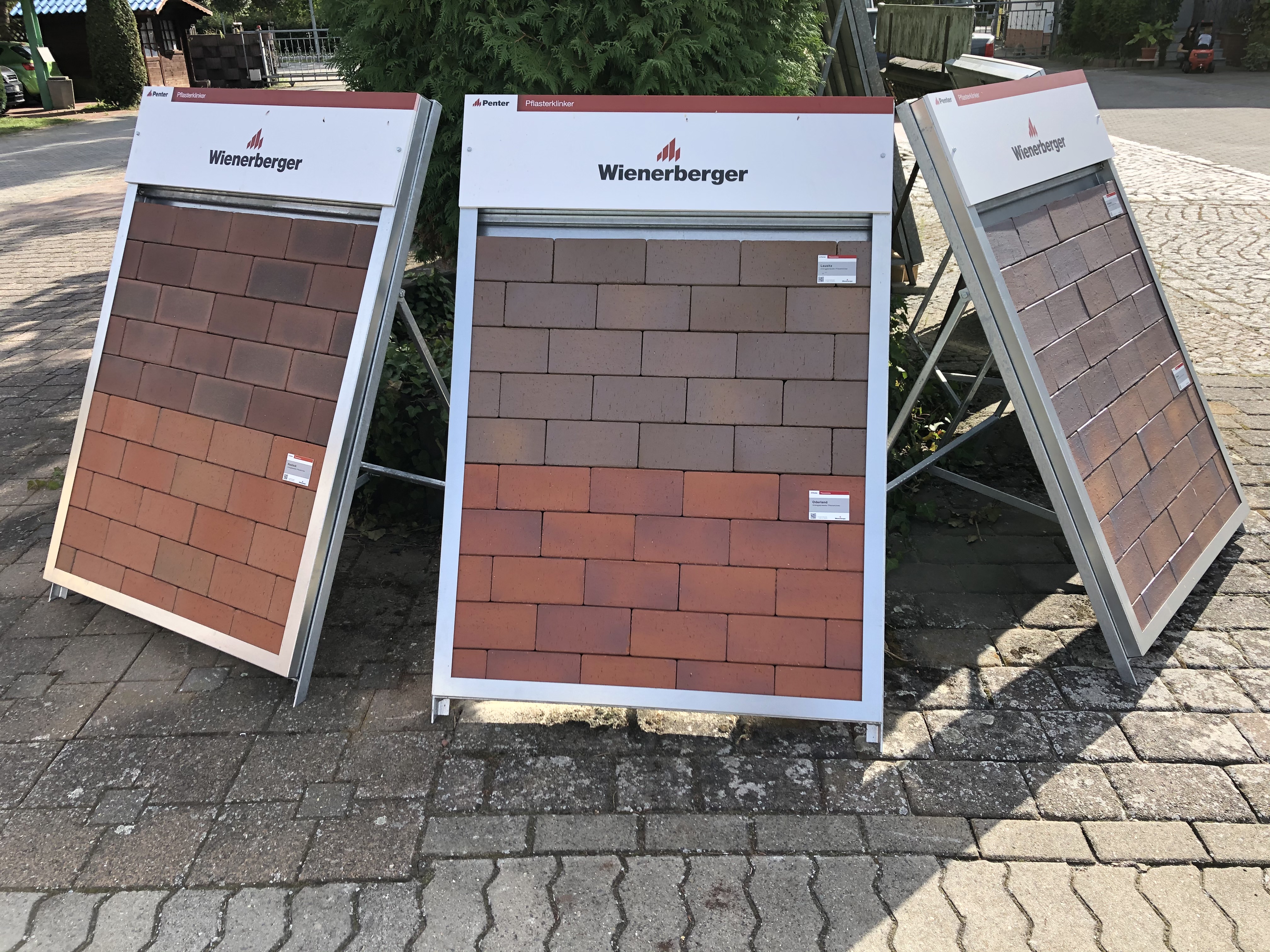 Drei Präsentationstafeln mit Wienerberger Ziegelmustern auf einem gepflasterten Außenbereich